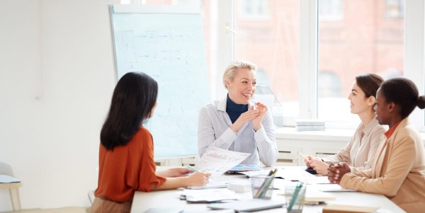 Group Of Smiling Businesswomen At Meeting Table