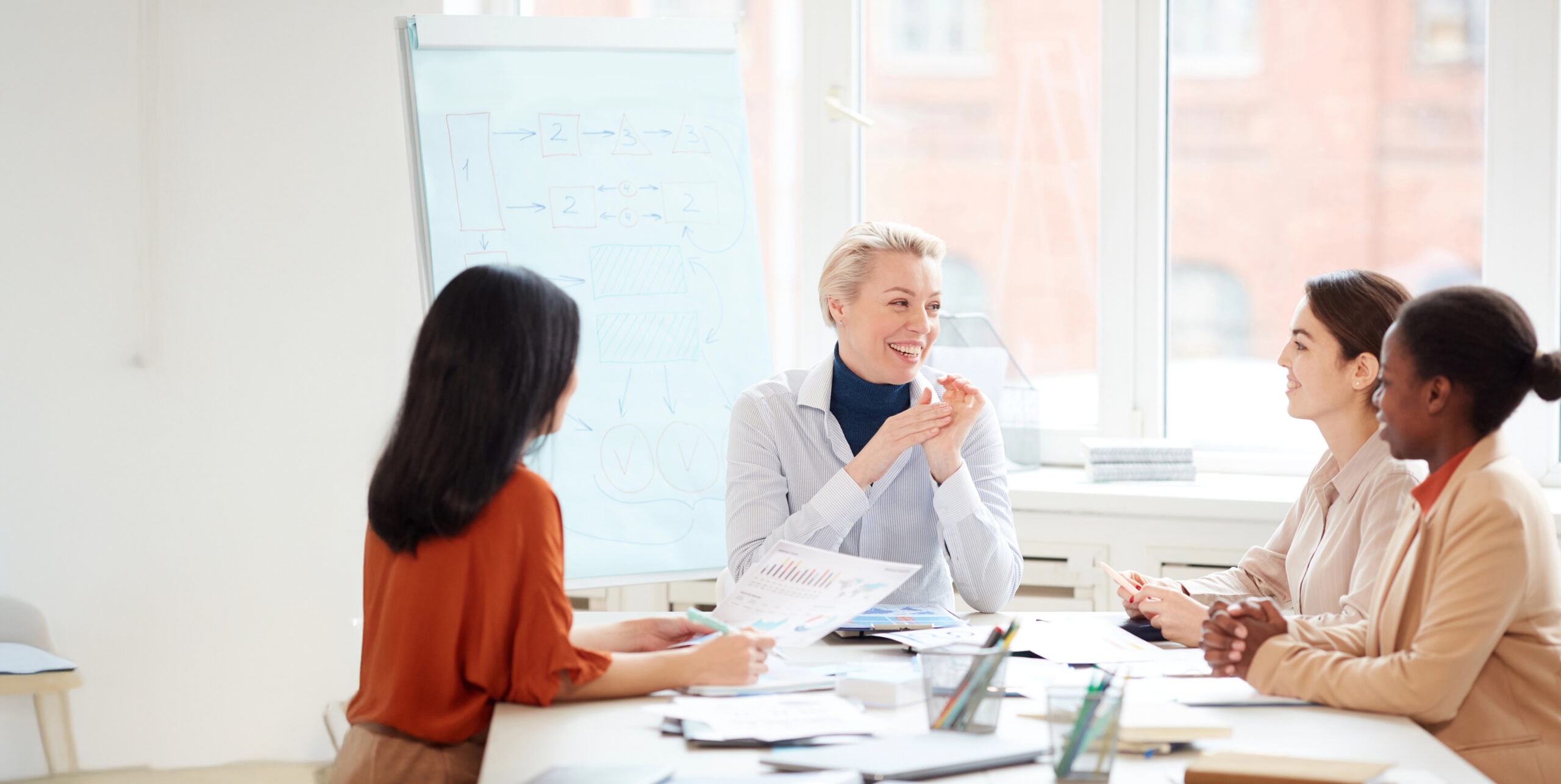 Group Of Smiling Businesswomen At Meeting Table