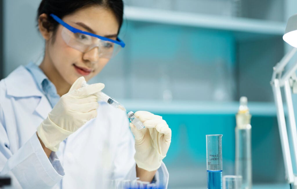 Female Scientist Carefully Extracting Liquid Sample From Bottle